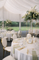Wesele w plenerze – eleganckie stoły pod namiotem Okrągłe stoły weselne pod namiotem z jasną zastawą, złotymi świecznikami i zieloną dekoracją.