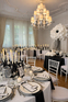 Sala weselna glamour z kryształowym żyrandolem Elegancka sala weselna z kryształowym żyrandolem, czarnymi krzesłami i stylowo nakrytymi stołami.