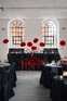 Wesele black tie z czerwonymi dekoracjami Elegancka sala weselna w stylu black tie z czarnymi stołami i czerwonymi kompozycjami kwiatowymi.